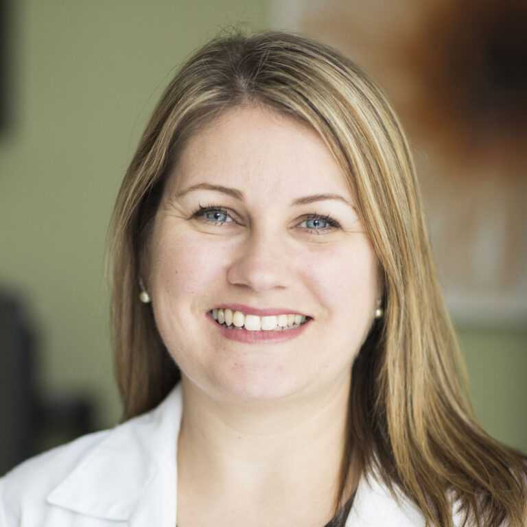 Headshot of Dr Carolyn Clevenger smiling, with an out of focus office wall in the background