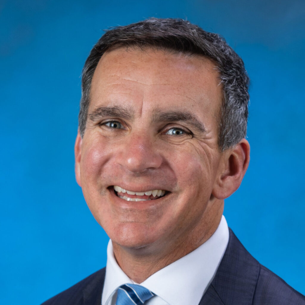 Headshot of Dr Chuck Vega smiling, with a simple blue background