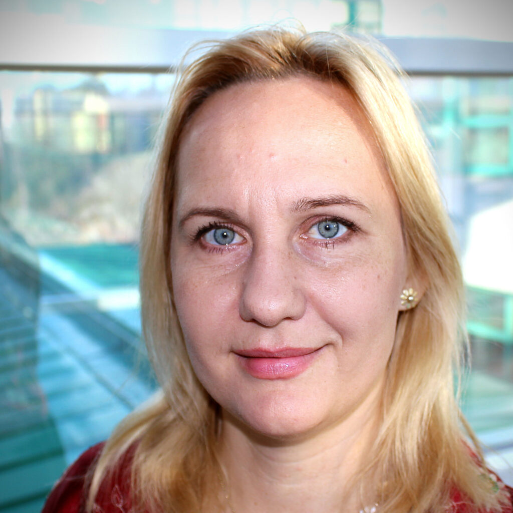 Headshot of Professor Dorota Religa smiling, with an out of focus indoor location in the background