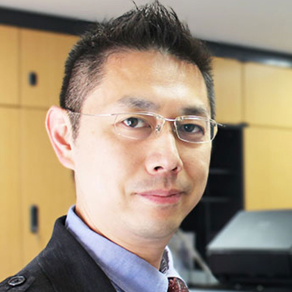 Headshot of Professor Hitoshi Shimada smiling, with an out of focus office in the background