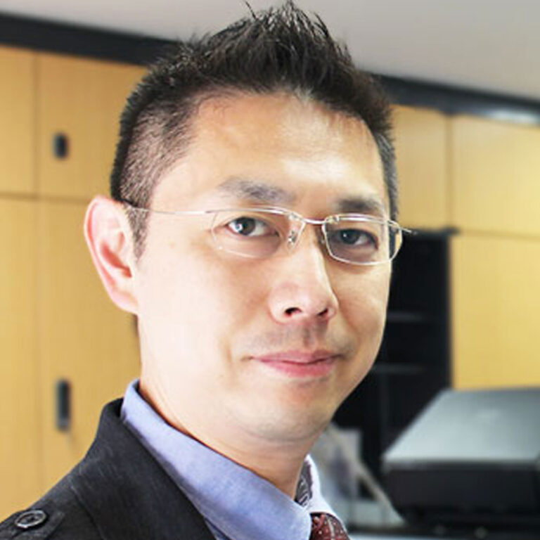 Headshot of Professor Hitoshi Shimada smiling, with an out of focus office in the background